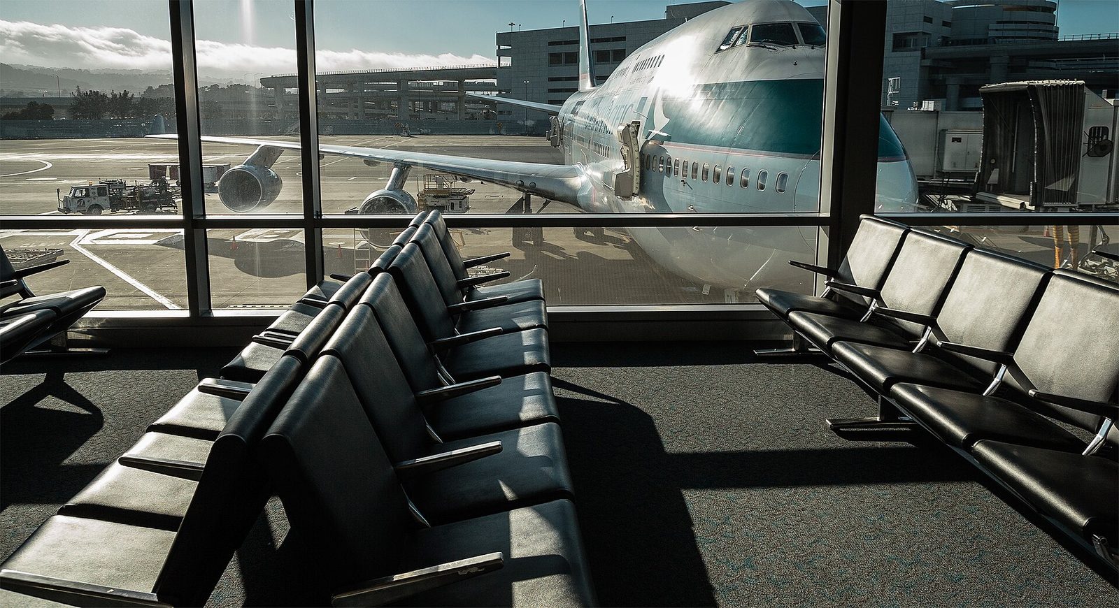 Empty seats at an airport gate, with a plane outside